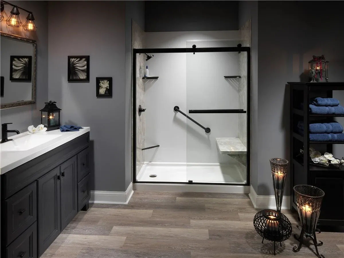 Modern bathroom with a glass-enclosed shower featuring black accents and a built-in bench. Dark wood cabinets, blue towels, and soft lighting create a cozy ambiance.