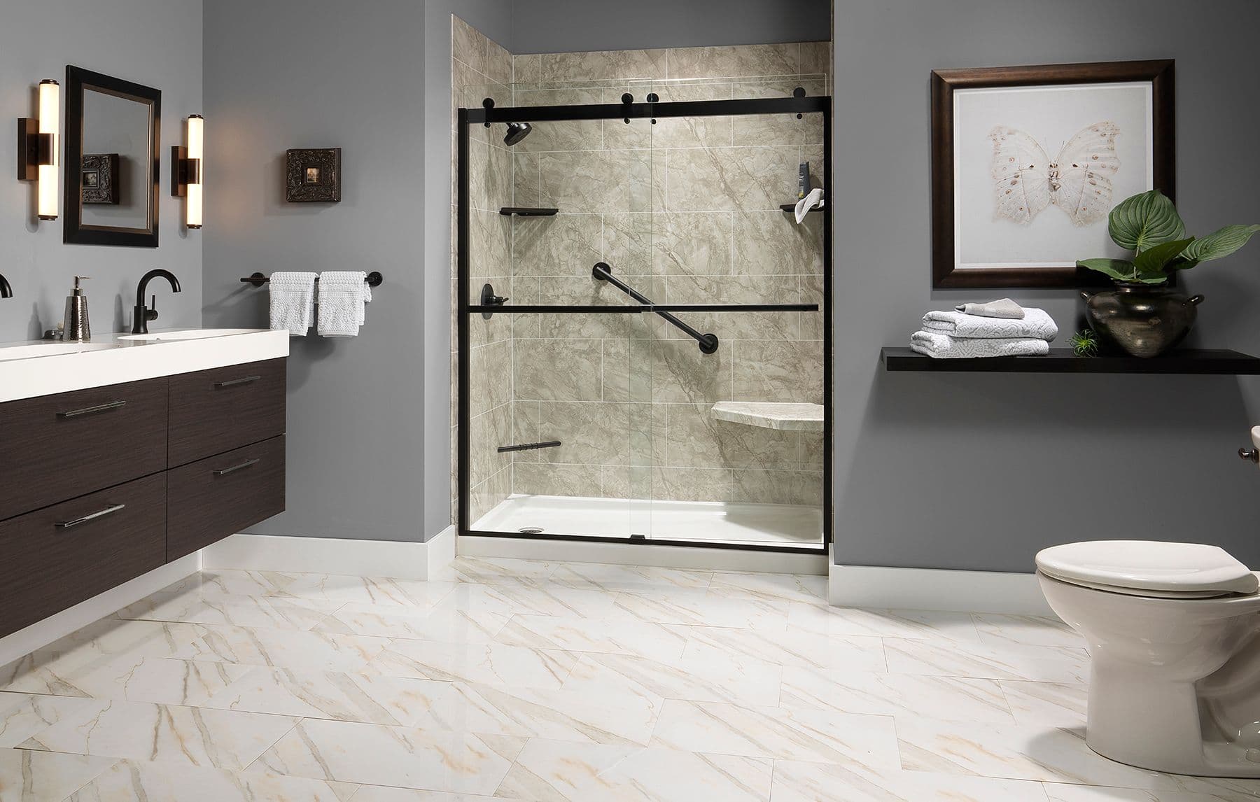 Modern bathroom with gray walls and marble floor. Features a spacious glass-enclosed shower, dark wood vanity with dual sinks, and a potted plant.